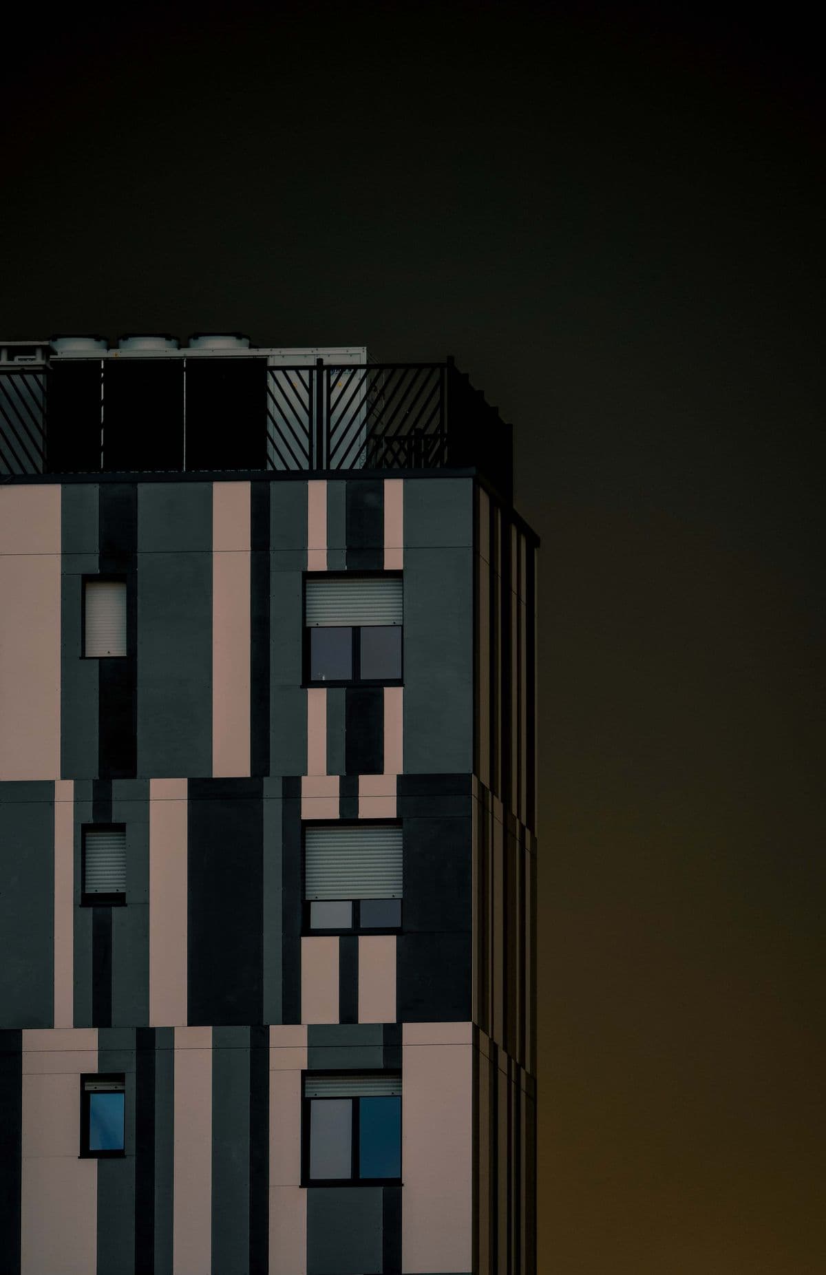 A dark, precisely detailed building facade rising into a gold dusk sky.
